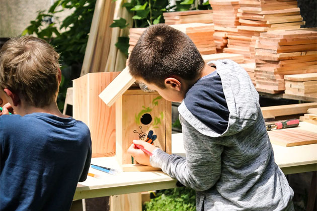 Des enfants en train de peindre sur des abris pour oiseaux